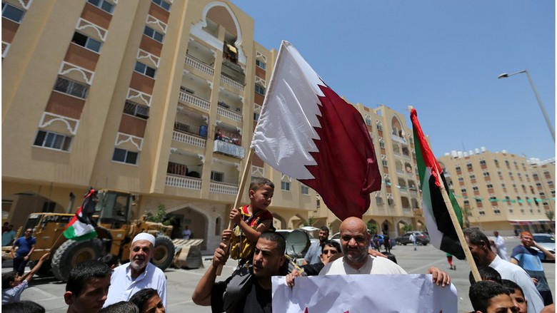 Seorang pria Palestina menggendong anaknya sembari memegang bendera Qatar dalam aksi mendukung Qatar di Jalur Gaza.
