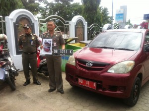 Kasat Satpol -PP Kota, Sahaya Mokoginta, memperlihatkan sejumlah Bukti-bukti berupa foto dan plat nomor mobil yang ditemukan pada mobil dinas Kaban BLH yang diamankan